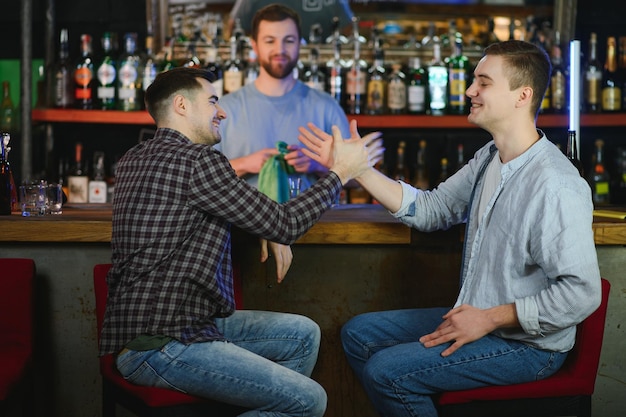 Amigos descansando no pub com cerveja nas mãos conversando