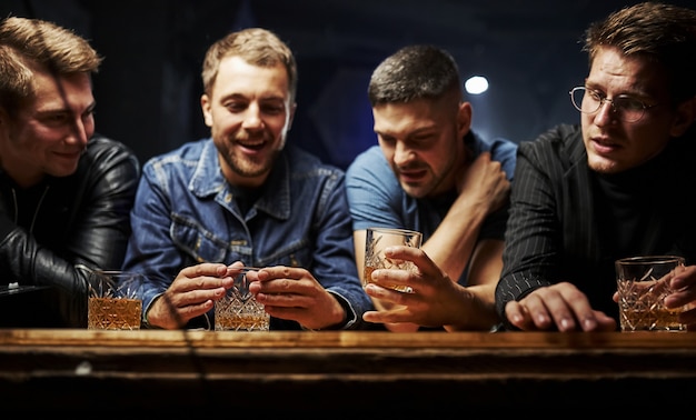 Amigos descansando en el pub con alcohol en las manos