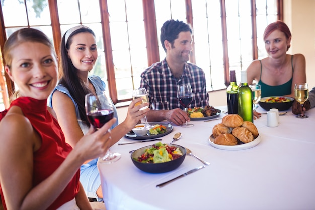 Amigos, desfrutando de comida e vinho na mesa no restaurante