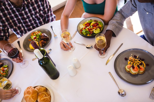 Foto amigos, desfrutando de comida e vinho na mesa no restaurante