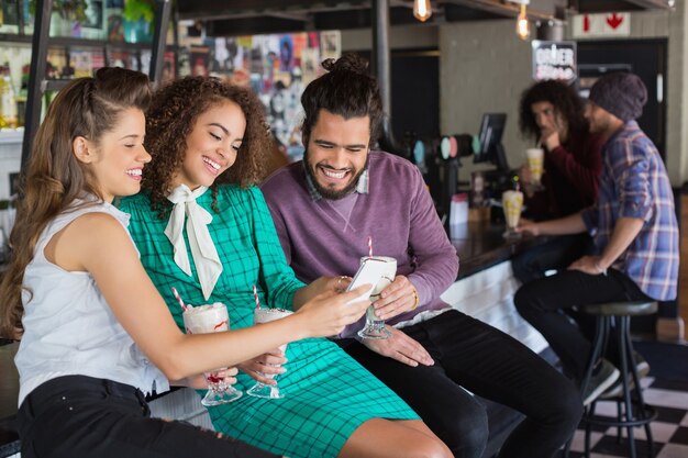 Amigos discutiendo sobre el móvil mientras beben en el restaurante