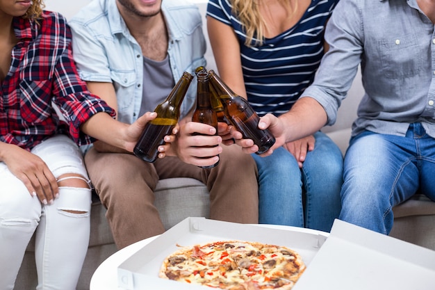 Amigos disfrutando de cerveza y pizza en casa