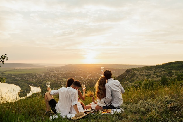 Foto amigos disfrutando de un día de picnic y beben vino blanco juntos.