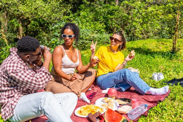 Amigos disfrutando de un picnic en el parque mientras toman fotos