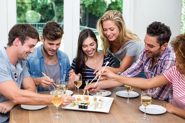 Amigos disfrutando de vino y sushi en casa