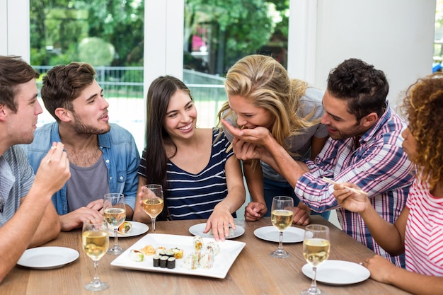 Amigos disfrutando de vino y sushi en casa