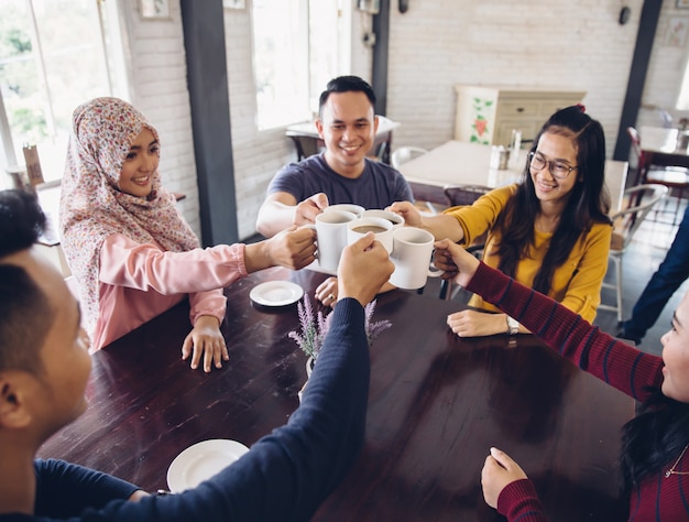 Amigos diversos felices que animan con café