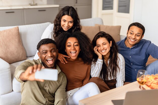 Amigos diversos tirando selfies no telefone celular na sala de estar