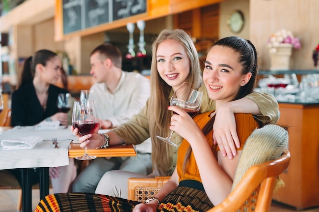 Los amigos se divierten bebiendo vino, hablando y sonriendo en el restaurante.