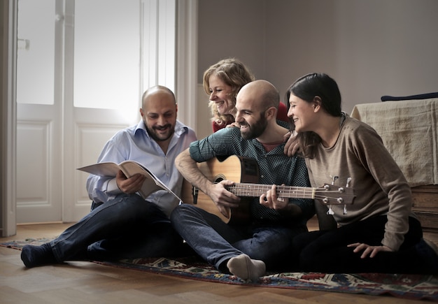 Amigos divirtiéndose con una guitarra en casa.