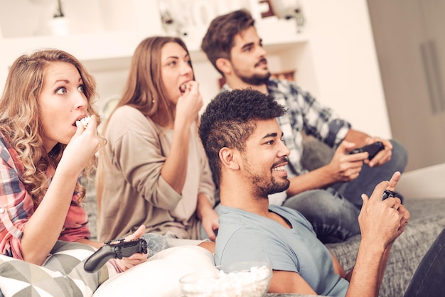 Amigos divirtiéndose en el sofá con videojuegos.