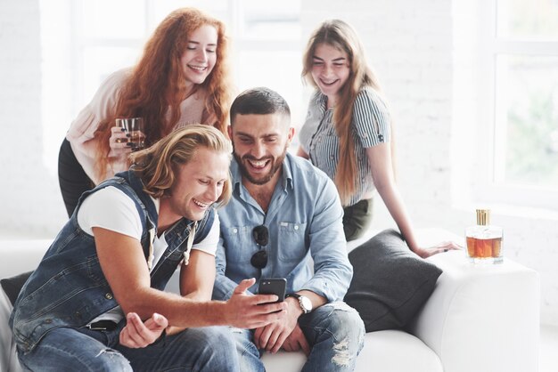 Amigos do escritório se divertem sentados no sofá branco