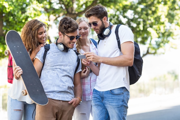 Amigos do quadril olhando para smartphone ao ar livre