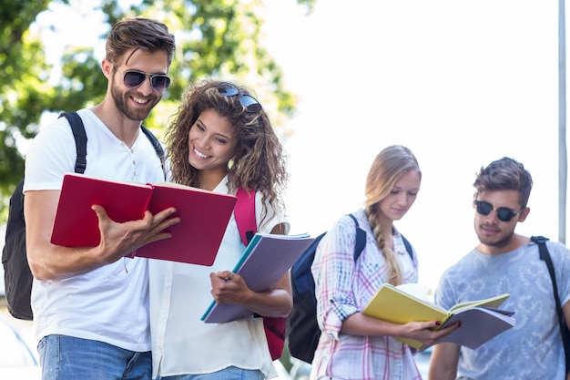 Foto amigos do quadril que leem notas em cadernos fora