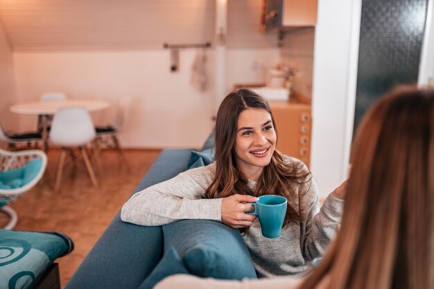 Amigos do sexo feminino em casa a beber chá.