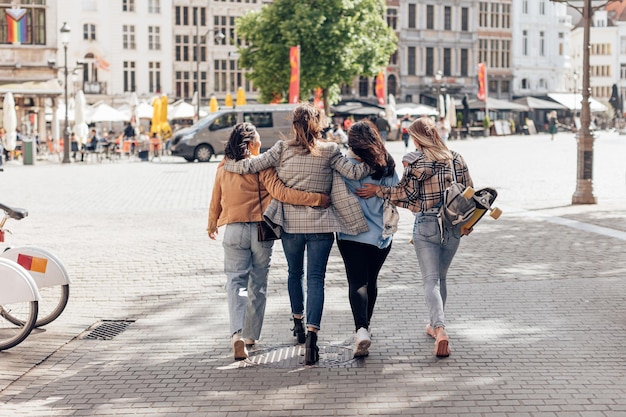 Amigos do sexo feminino jovens andando embrac no centro da cidade