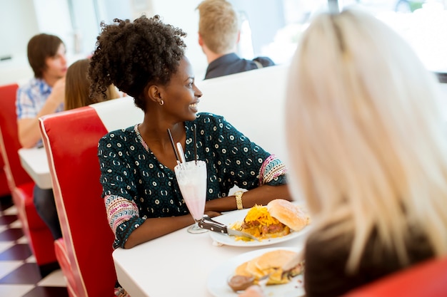 Amigos do sexo feminino multirraciais comendo fast-food em uma mesa na lanchonete