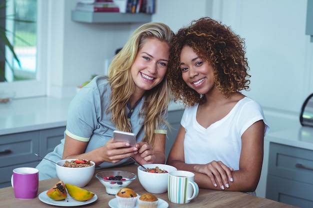 Amigos do sexo feminino sorridente, sentado à mesa do café da manhã