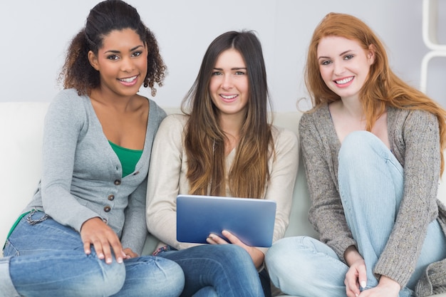 Amigos do sexo feminino usando tablet digital juntos no sofá