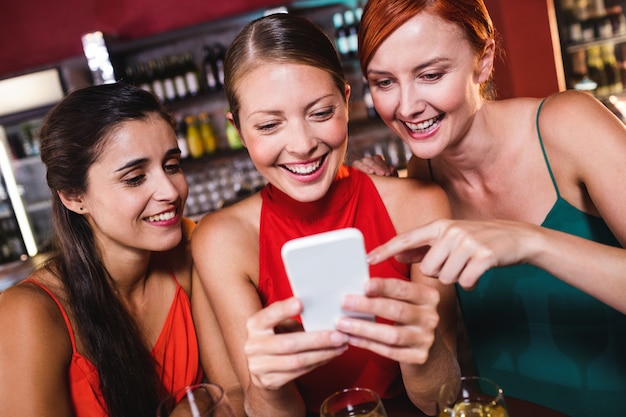 Amigos do sexo feminino usando telefone celular enquanto desfruta de vinho