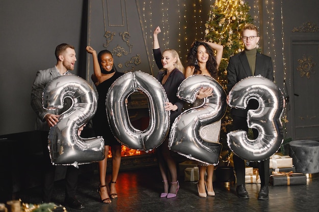 Amigos do sexo masculino e feminino em pé com balões 2023 para a celebração do Ano Novo