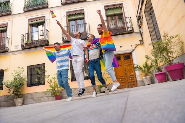 Amigos do sexo masculino homossexuais pulando de alegria na diversidade da festa do orgulho gay de jovens na estrada da cidade para a manifestação com o conceito lgbt de bandeiras de arco-íris