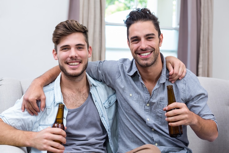 Foto amigos do sexo masculino jovens felizes desfrutando de cerveja enquanto está sentado no sofá