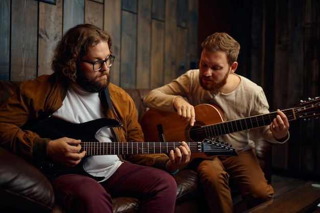 Amigos do sexo masculino tocando violão em casa juntos