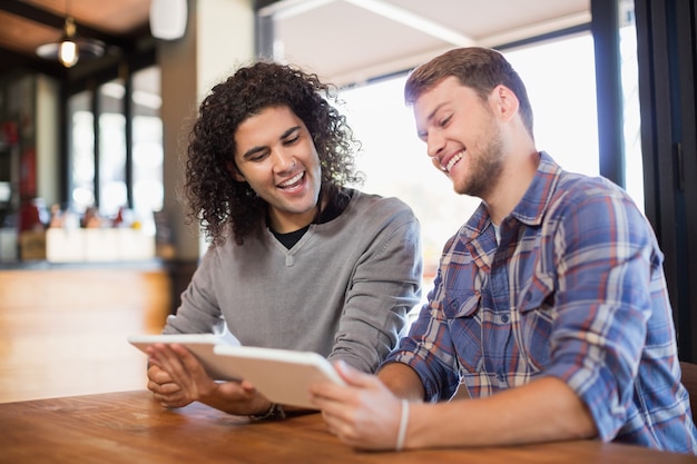 Amigos do sexo masculino usando tablets digitais em restaurante