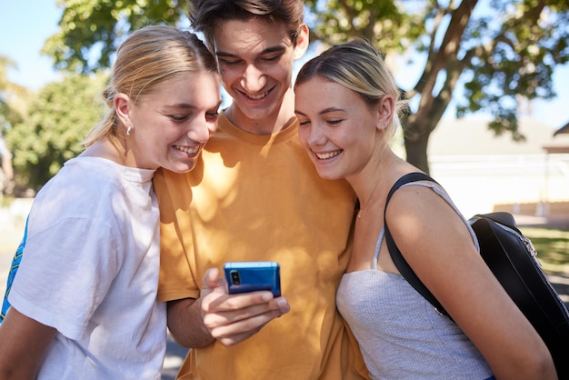 Amigos do telefone e mídia social em um parque com um grupo de homens e mulheres lendo uma mensagem de texto juntos ao ar livre Comunicação de tecnologia móvel 5g e amizade com estudantes universitários