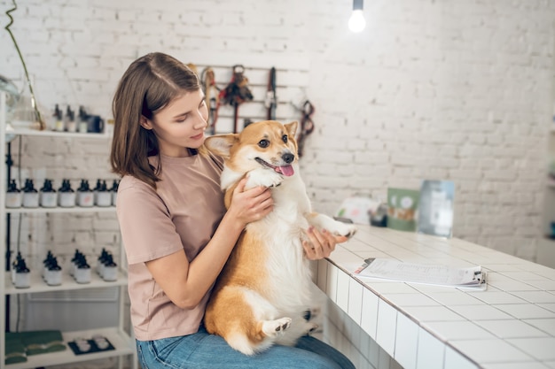 Amigos. Dueña de mascota joven sosteniendo a su perro y sintiéndose feliz