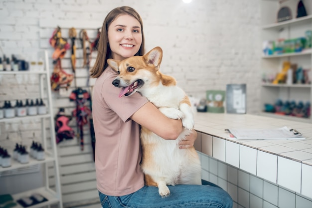 Amigos. Dueña de mascota joven sosteniendo a su perro y sintiéndose feliz