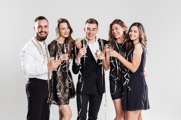 Foto amigos em roupas elegantes e elegantes sorriem juntos segurando taças de champanhe nas mãos