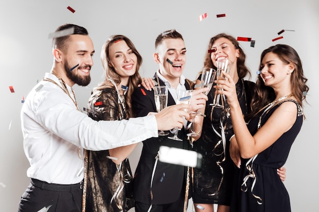 Amigos em roupas elegantes e elegantes sorriem juntos segurando taças de champanhe nas mãos