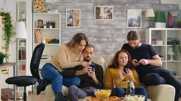 Amigos em telefones na acolhedora sala de estar brilhante.