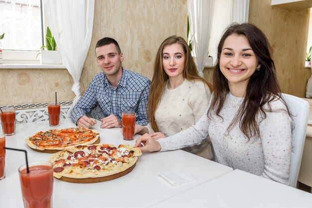 Amigos em um café comendo pizza e posando para a câmera