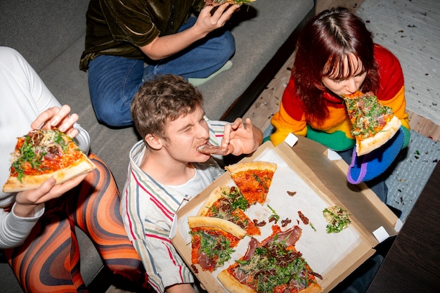 Foto amigos em uma festa com uma pizza deliciosa