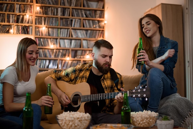 Foto amigos em uma festa em casa tocando violão e se divertindo