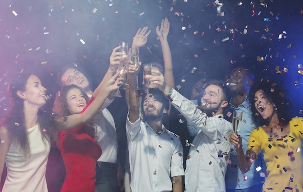 Amigos emocionados tintineo de copas de champán en la fiesta de cumpleaños