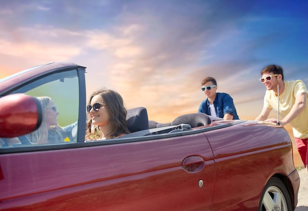 Amigos empujando un coche descapotable roto