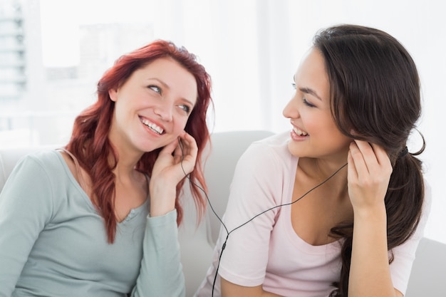 Amigos escuchando música a través de auriculares juntos en casa