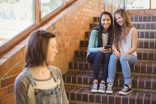 Foto amigos de la escuela intimidando a una niña triste en el pasillo de la escuela