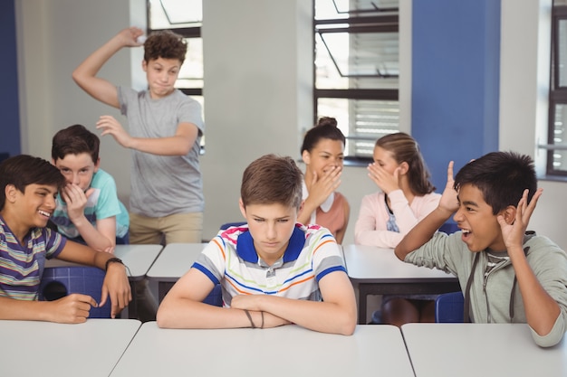 Amigos de la escuela intimidando a un niño triste en el aula