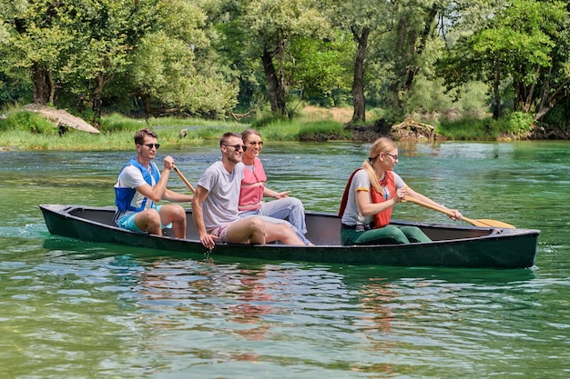 Amigos exploradores aventureiros do grupo estão canoando em um rio selvagem cercado pela bela natureza