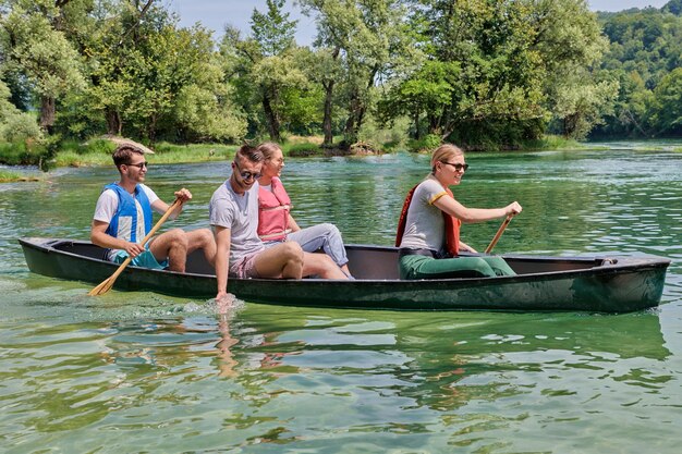 Amigos exploradores aventureiros do grupo estão canoando em um rio selvagem cercado pela bela natureza