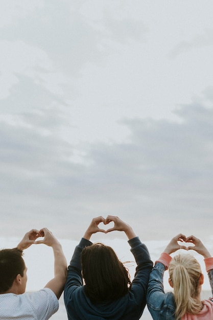 Amigos fazendo amor com mãos de coração na praia