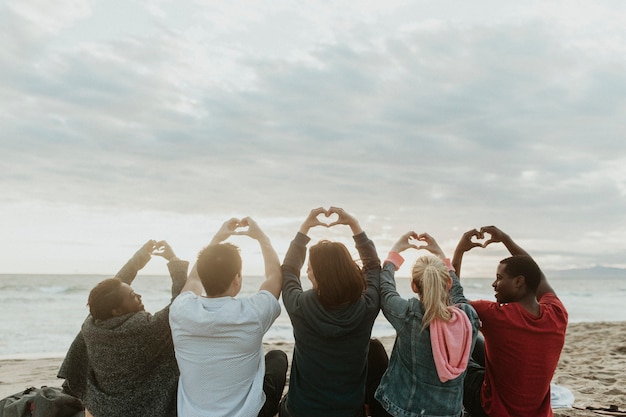 Amigos fazendo amor com mãos de coração na praia