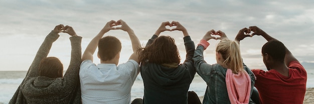 Amigos fazendo amor com mãos de coração na praia