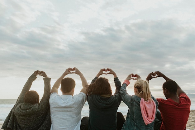 Amigos fazendo amor com mãos de coração na praia