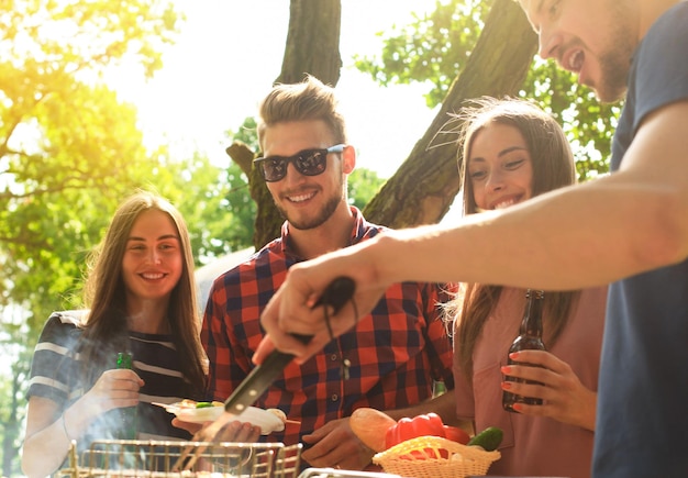 Foto amigos felices asando carne y disfrutando de una barbacoa al aire libre